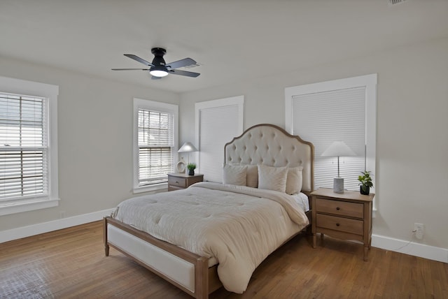 bedroom featuring baseboards, wood finished floors, and a ceiling fan