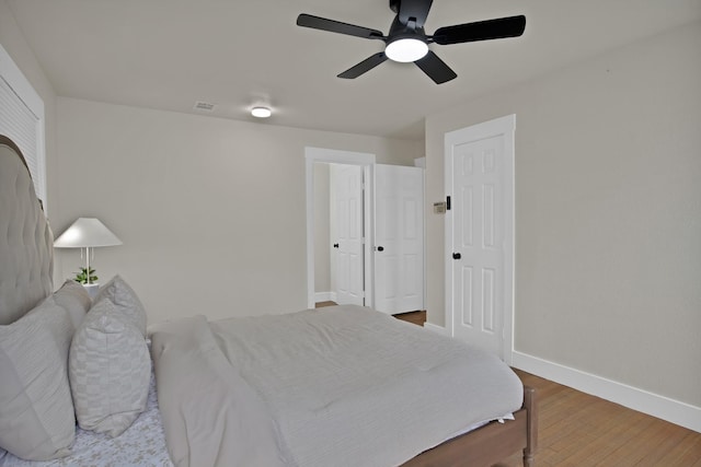 bedroom featuring ceiling fan, visible vents, baseboards, and wood finished floors