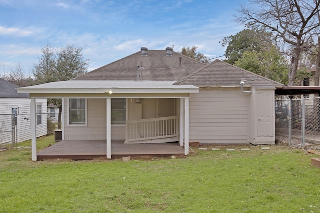 rear view of property featuring a yard, a wooden deck, a shingled roof, and fence