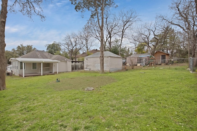 view of yard with an outbuilding, a storage unit, and fence