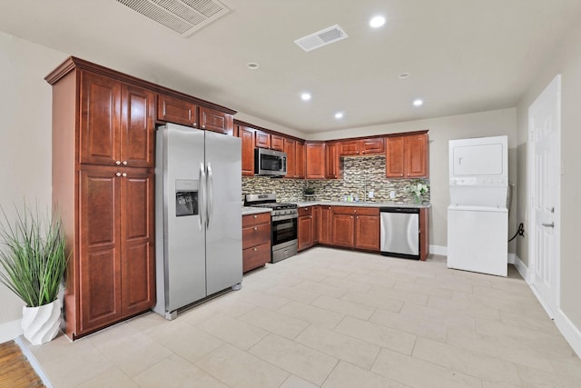 kitchen with sink, stainless steel appliances, backsplash, and stacked washer / drying machine