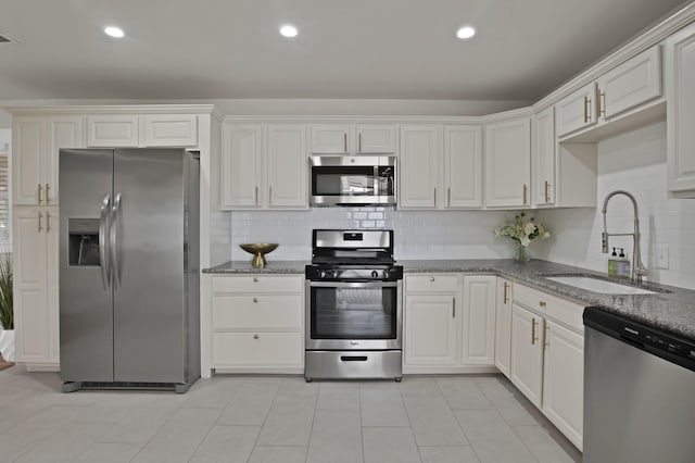 kitchen with white cabinets, appliances with stainless steel finishes, stone countertops, and a sink