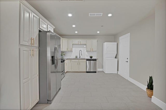 kitchen featuring a sink, recessed lighting, appliances with stainless steel finishes, light countertops, and stacked washer / dryer