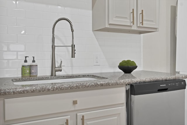 kitchen featuring a sink, backsplash, dark stone counters, and stainless steel dishwasher