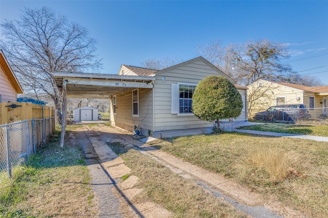 view of front of house with a storage unit, a front yard, and a carport