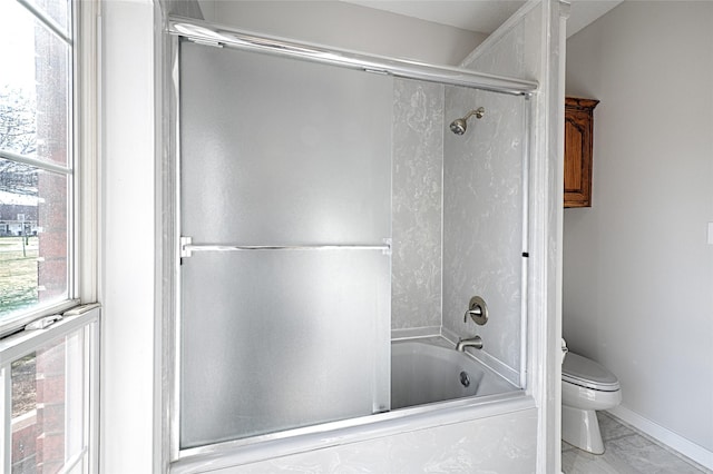 bathroom with toilet and shower / bath combination with glass door