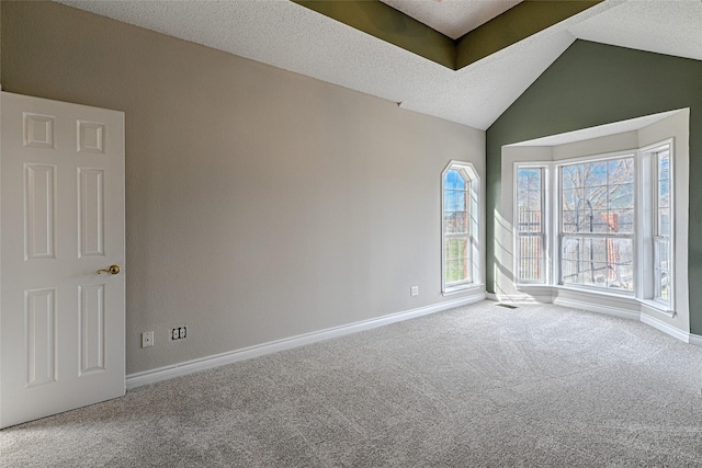 carpeted empty room with a textured ceiling and vaulted ceiling