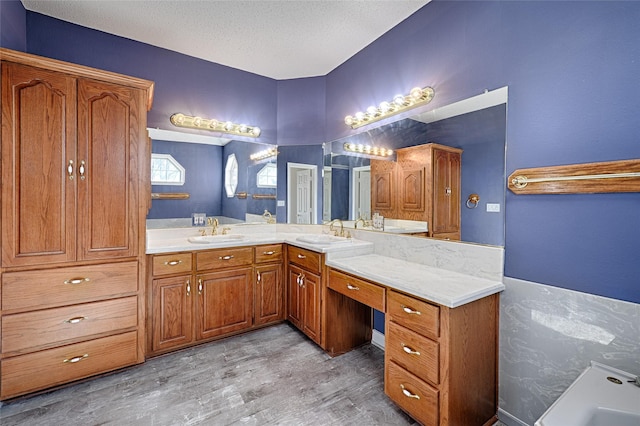 bathroom featuring hardwood / wood-style floors, vanity, a bathtub, and a textured ceiling