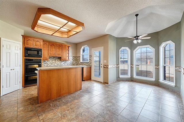 kitchen featuring backsplash, a textured ceiling, ceiling fan, black appliances, and a center island