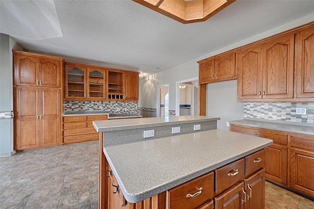 kitchen featuring decorative backsplash, a center island, and a textured ceiling