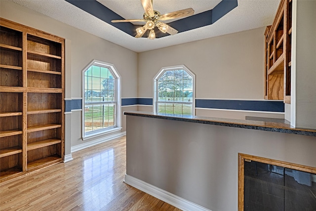 unfurnished office featuring ceiling fan, light hardwood / wood-style flooring, and a textured ceiling