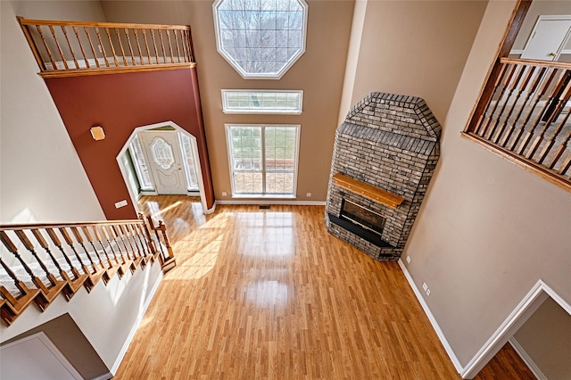 foyer with a fireplace, a towering ceiling, and wood-type flooring