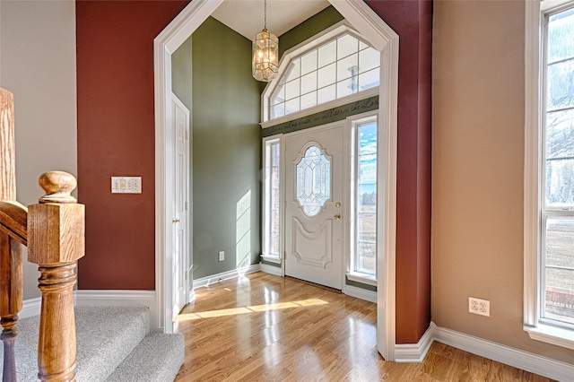 foyer with a wealth of natural light, an inviting chandelier, and light wood-type flooring