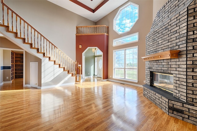 unfurnished living room with a fireplace, a high ceiling, and light hardwood / wood-style floors