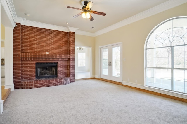 unfurnished living room featuring a ceiling fan, light colored carpet, ornamental molding, french doors, and a fireplace