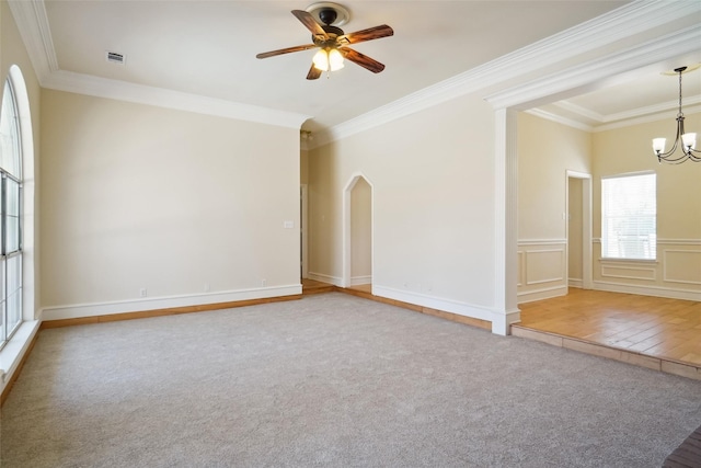 empty room with visible vents, arched walkways, crown molding, carpet flooring, and ceiling fan with notable chandelier