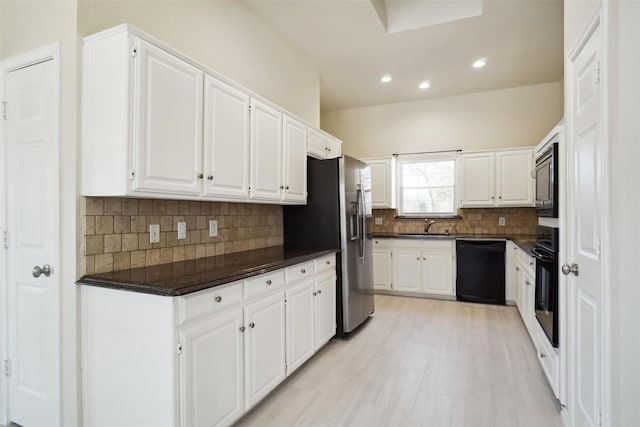 kitchen featuring black appliances, backsplash, a sink, and white cabinetry