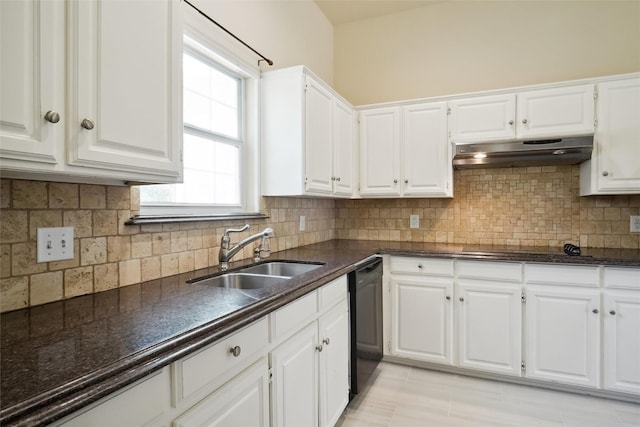 kitchen with dark countertops, white cabinetry, a sink, and under cabinet range hood