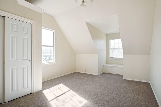 bonus room featuring lofted ceiling, light colored carpet, and baseboards