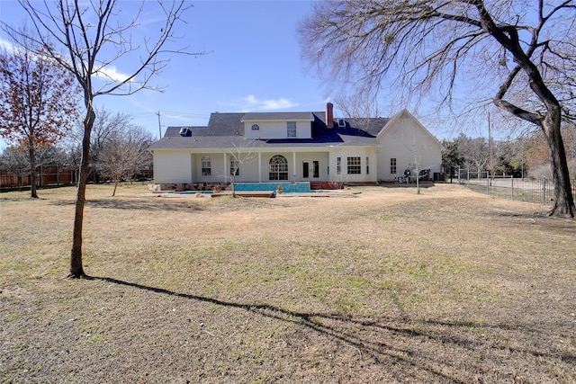 rear view of house with a lawn, a chimney, and fence