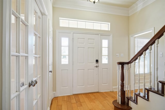 entryway featuring ornamental molding, light wood-style floors, and stairs