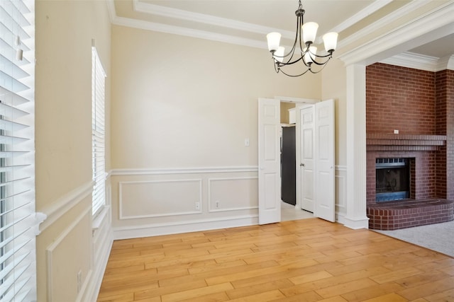 unfurnished dining area featuring light wood-style floors, a brick fireplace, and crown molding