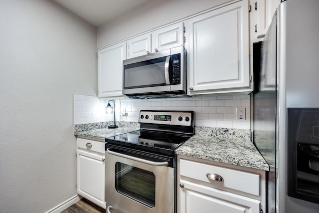 kitchen with tasteful backsplash, appliances with stainless steel finishes, white cabinets, and light stone counters