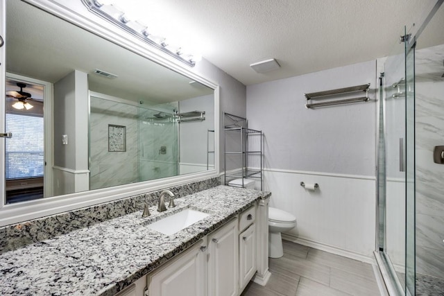 bathroom featuring a shower with shower door, vanity, toilet, and a textured ceiling