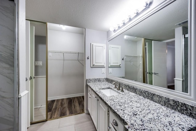 bathroom featuring a textured ceiling, tile patterned floors, and vanity