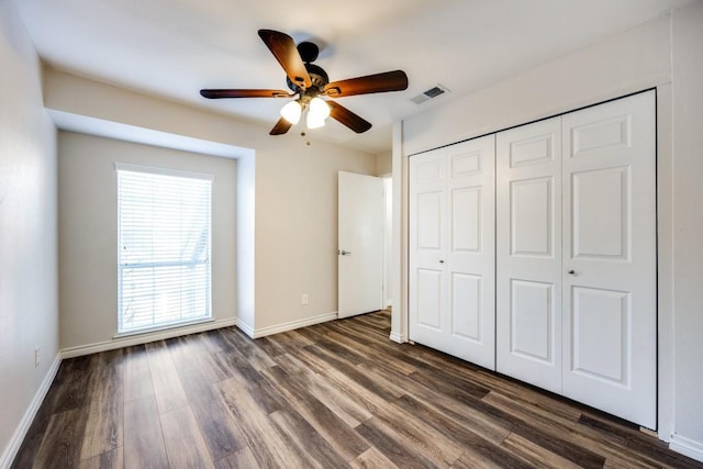 unfurnished bedroom featuring ceiling fan, dark hardwood / wood-style flooring, and a closet