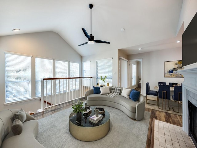 living room featuring vaulted ceiling, ceiling fan, a fireplace, and wood-type flooring