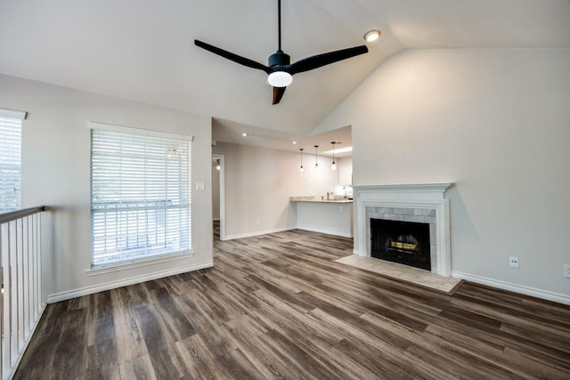 unfurnished living room with vaulted ceiling, ceiling fan, dark hardwood / wood-style flooring, and a tile fireplace