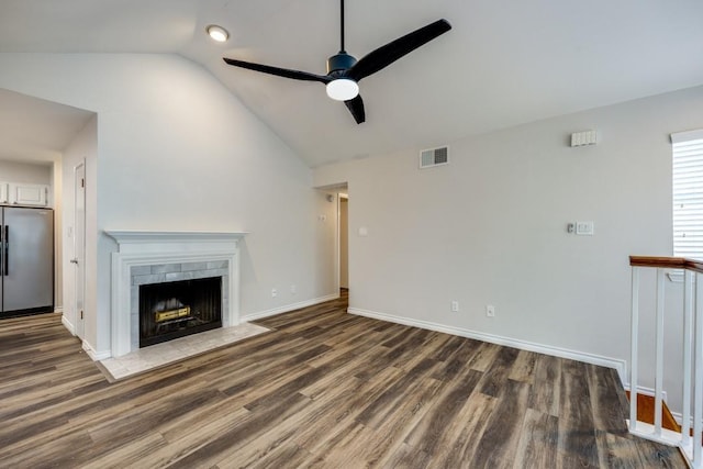 unfurnished living room with ceiling fan, vaulted ceiling, a fireplace, and dark hardwood / wood-style flooring