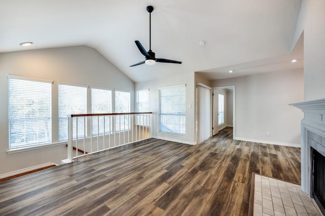 unfurnished living room featuring vaulted ceiling, dark wood-type flooring, a tile fireplace, and ceiling fan