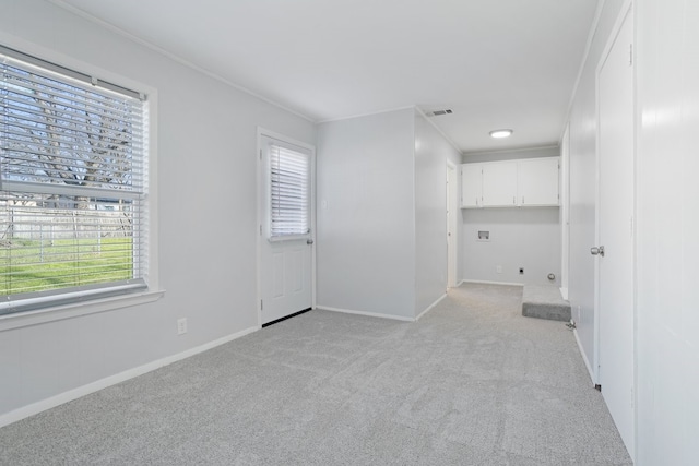 spare room with light carpet, plenty of natural light, and ornamental molding