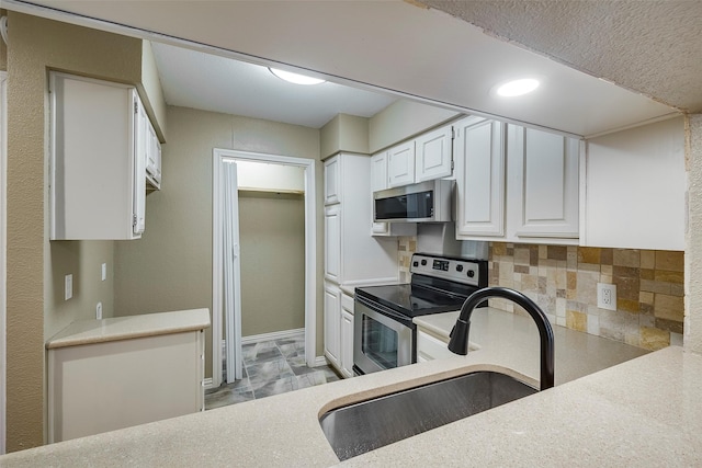 kitchen with appliances with stainless steel finishes, tasteful backsplash, white cabinetry, and sink