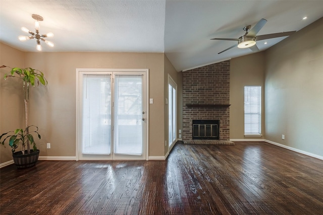 unfurnished living room featuring lofted ceiling, a brick fireplace, dark hardwood / wood-style floors, and a healthy amount of sunlight