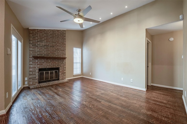 unfurnished living room featuring ceiling fan, a brick fireplace, lofted ceiling, and dark hardwood / wood-style flooring