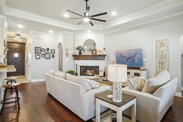 living room with a fireplace, ceiling fan, dark hardwood / wood-style flooring, and ornamental molding