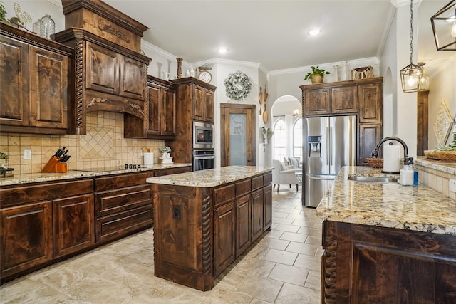 kitchen with appliances with stainless steel finishes, a kitchen island, and dark brown cabinets