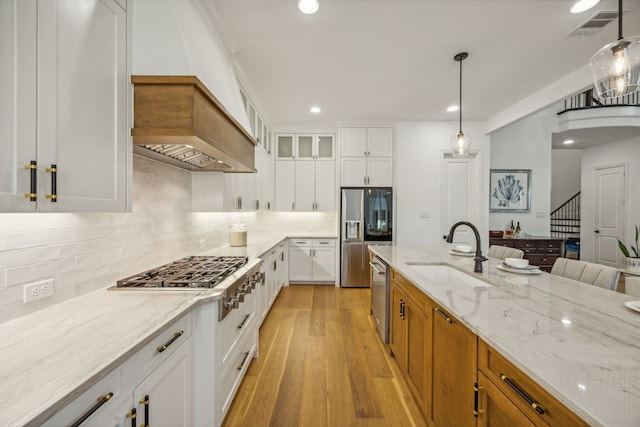 kitchen featuring light stone counters, a sink, visible vents, light wood-style floors, and appliances with stainless steel finishes