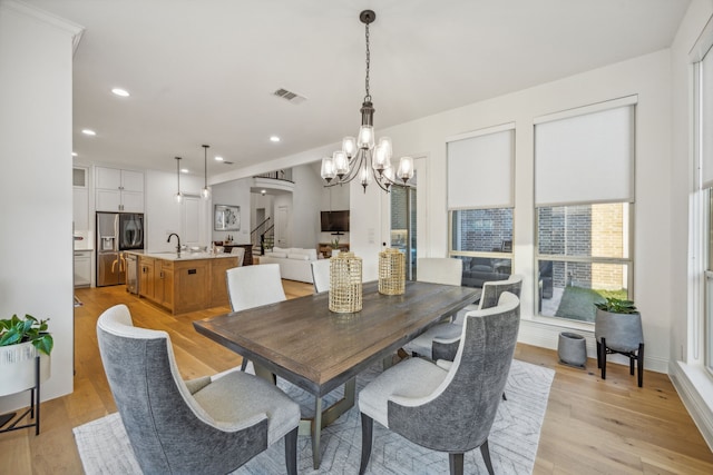 dining area featuring arched walkways, light wood-style flooring, stairway, and visible vents