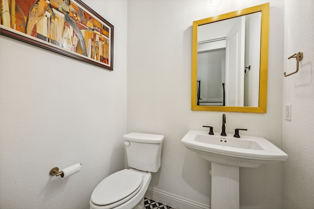 bathroom with toilet, baseboards, and a sink