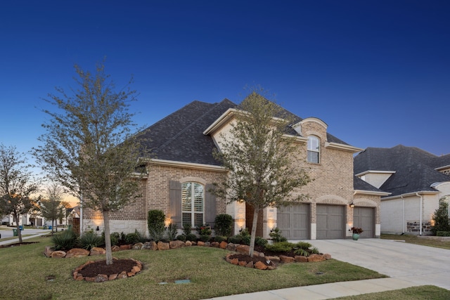 french country inspired facade featuring a front lawn, brick siding, driveway, and an attached garage