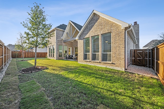 rear view of house with a yard, a fenced backyard, a chimney, and brick siding