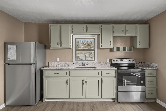 kitchen featuring light stone countertops, appliances with stainless steel finishes, a sink, and light wood finished floors