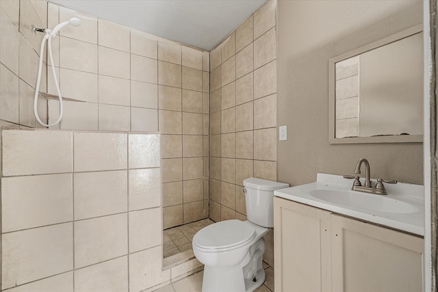 bathroom featuring a tile shower, tile patterned floors, vanity, and toilet