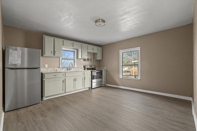 kitchen with stainless steel appliances, a healthy amount of sunlight, sink, and light hardwood / wood-style floors