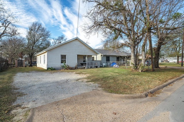 view of front of property with dirt driveway, covered porch, and a front yard