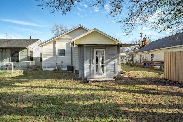 rear view of property with central air condition unit, a storage shed, and a lawn